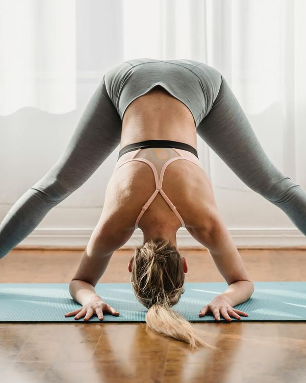 Woman in a peaceful posture on a light background, symbolizing calm and flexibility.